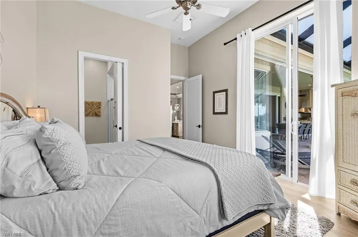 Bedroom with light wood-style flooring, access to exterior, ceiling fan, and ensuite bath