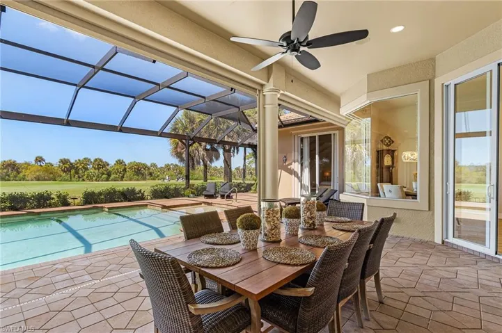 View of patio / terrace featuring a sunroom, an outdoor pool, outdoor dining area, glass enclosure, and ceiling fan