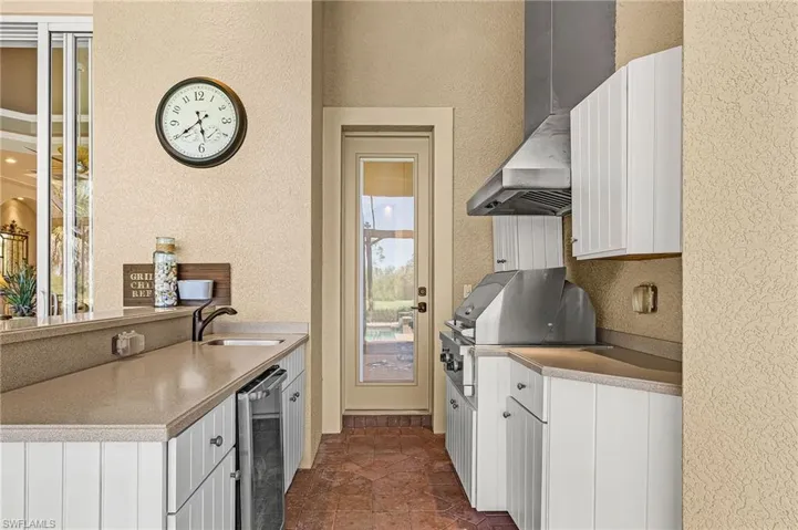 Outdoor Kitchen featuring white cabinets, a textured wall, a peninsula, stainless steel dishwasher, and light stone counters