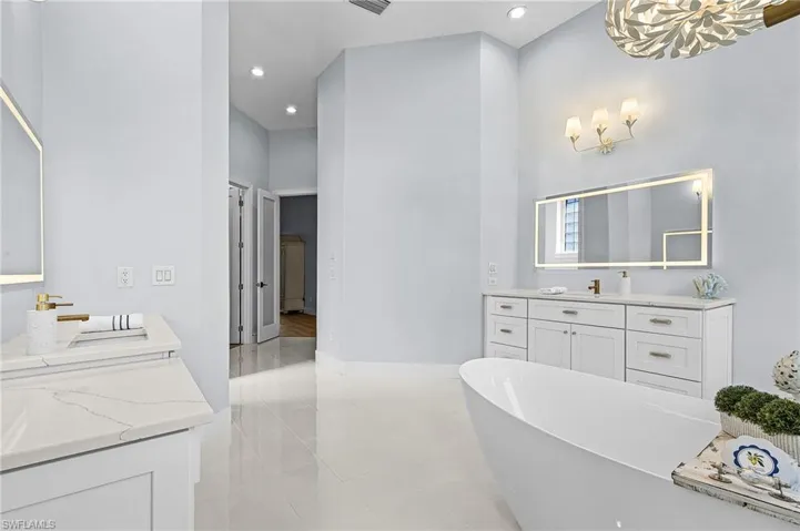Primary Bathroom with vanity, a freestanding tub, a high ceiling, and recessed lighting