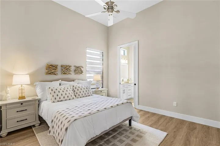 Bedroom with light wood-style floors, connected bathroom, and a ceiling fan