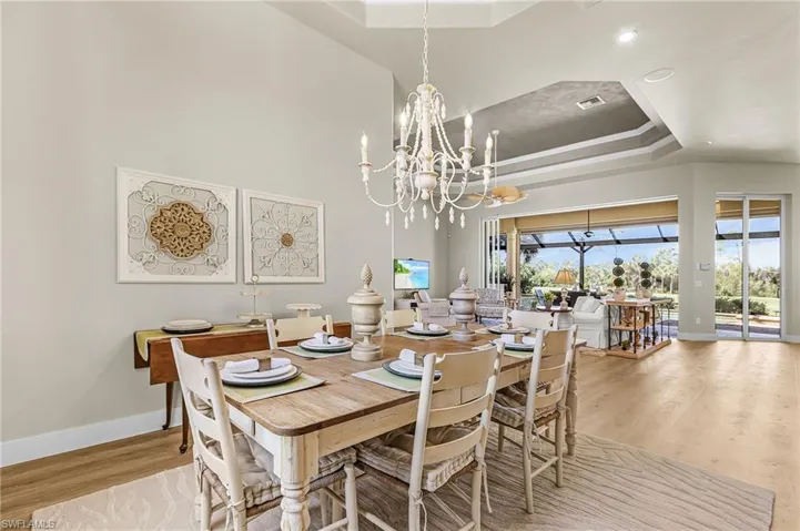 Dining area featuring a raised ceiling, light wood-style floors, and suspended lighting