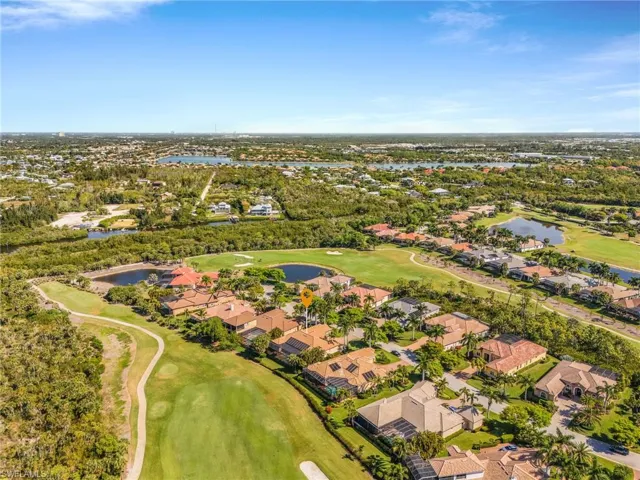 Aerial perspective of suburban area with a nearby body of water and a golf course