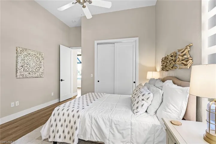 Bedroom with wood finished floors, a ceiling fan, a closet, and a high ceiling