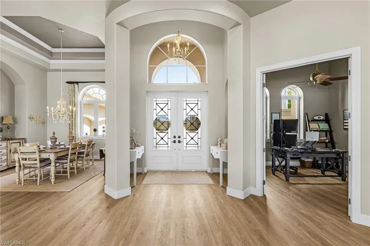 Entrance foyer featuring a chandelier, light wood finished floors, a ceiling fan, a high ceiling, and crown molding