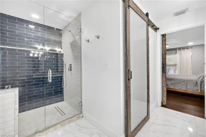 Ensuite bathroom with marble look tile flooring, a stall shower, and recessed lighting
