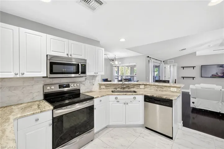 Kitchen featuring stainless steel appliances, open floor plan, decorative backsplash, white cabinets, and recessed lighting