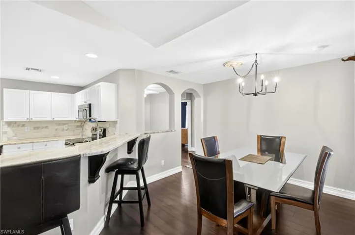 Dining room featuring arched walkways, dark wood-type flooring, a chandelier, and recessed lighting