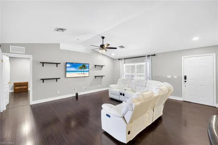 Living room featuring dark wood-style flooring, lofted ceiling, and ceiling fan