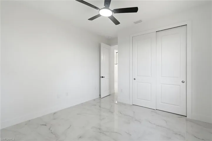White interior with a black ceiling fan, white paneled doors, and white tile flooring