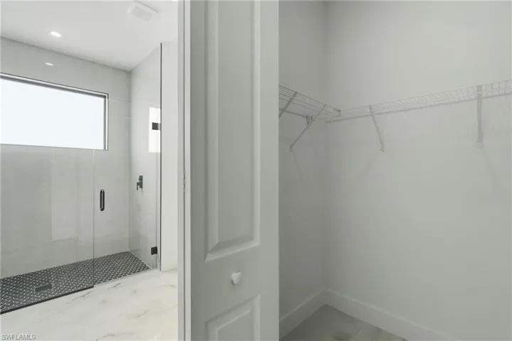 Full walk-in shower with black hexagonal tile flooring and clear glass enclosure