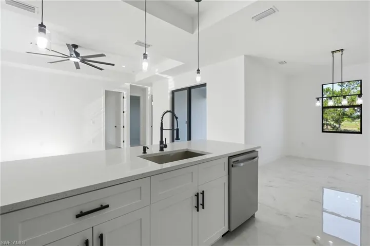 White cabinetry with sleek black hardware, stainless steel dishwasher, and a large kitchen island with an undermount sink