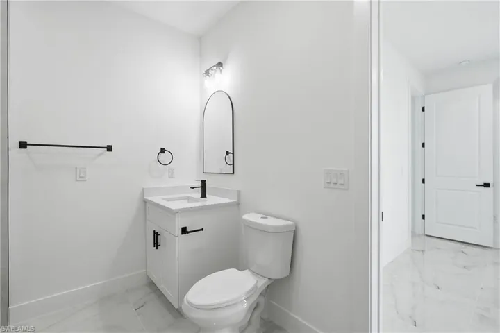 White vanity with a rectangular basin, black wall-mounted faucet, and black hardware