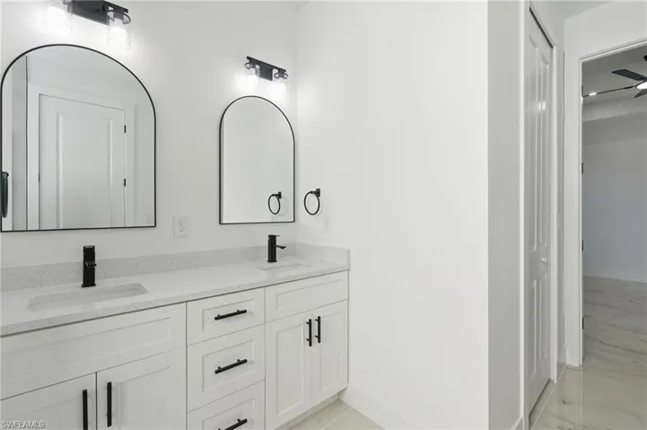 Double vanity with white cabinetry, matte black hardware, and integrated sinks