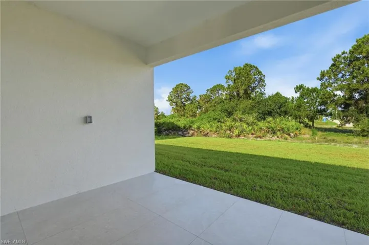 Covered patio featuring a smooth ceiling, textured wall, and light-toned tile flooring