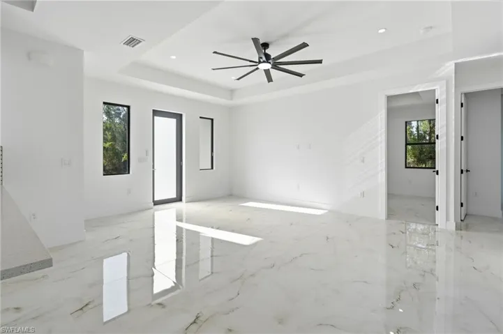 Spacious room featuring large format tile flooring, a tray ceiling, recessed lighting, and an oversized ceiling fan