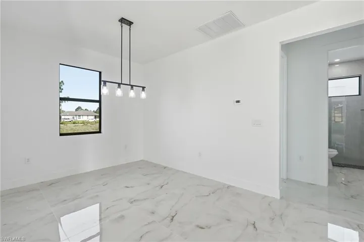 White walls, a rectangular window with a black frame, and a matte black linear chandelier with exposed bulbs