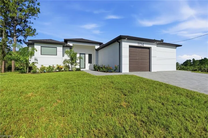 Contemporary single-story residence featuring a white stucco exterior, dark brown garage door, and a paved driveway