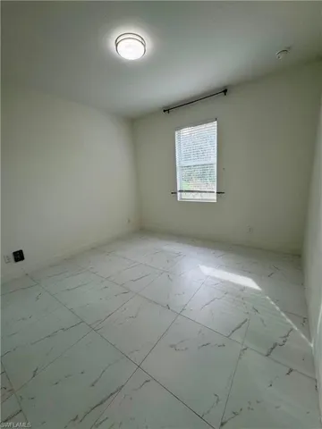 Unfurnished room featuring light marble finish floors and baseboards