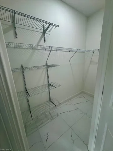 Walk in closet featuring light marble finish floors