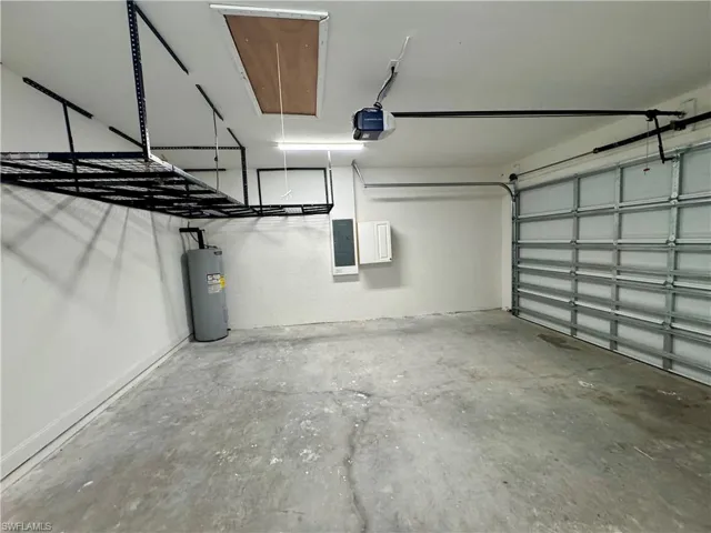 Garage featuring electric panel, water heater, and a garage door opener