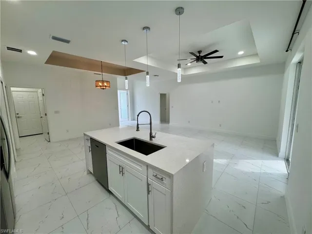 Kitchen with a tray ceiling, white cabinetry, ceiling fan, decorative light fixtures, and recessed lighting