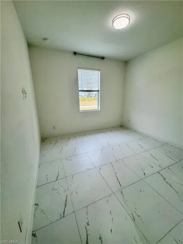 Empty room featuring a textured ceiling and light marble finish flooring