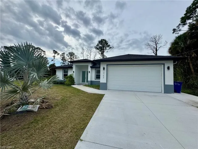 View of front of house featuring stucco siding, a front lawn, concrete driveway, and an attached garage
