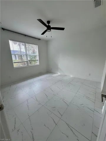 Empty room with light marble finish floors and ceiling fan