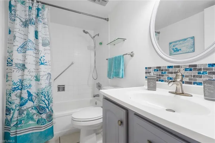 Full bathroom featuring decorative backsplash, toilet, newer vanity, and shower / tub combo with curtain