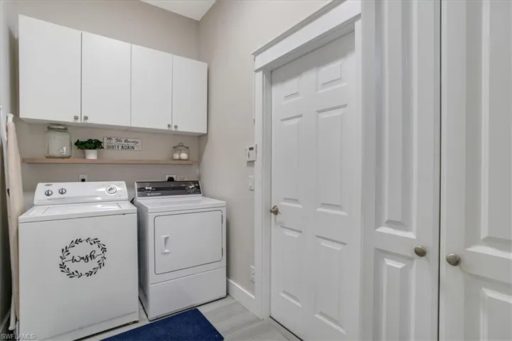 Clothes washing area featuring washer and dryer, cabinets, and light wood-type flooring