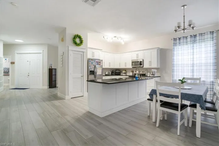 Kitchen with white cabinetry, hanging light fixtures, light wood-type flooring, stainless steel appliances, and rail lighting
