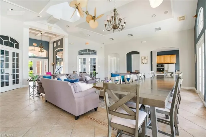 Clubhouse dining space featuring a notable chandelier, light tile floors, a raised ceiling, and french doors