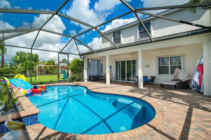 View of pool featuring a patio, glass enclosure, and ceiling fan