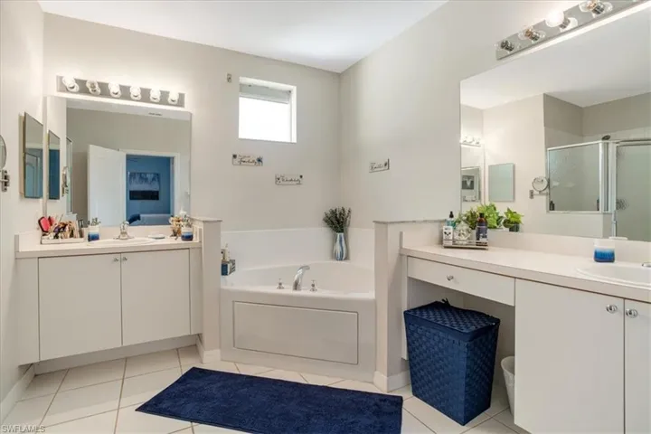 Bathroom featuring a bath to relax in, vanity with extensive cabinet space, and tile floors
