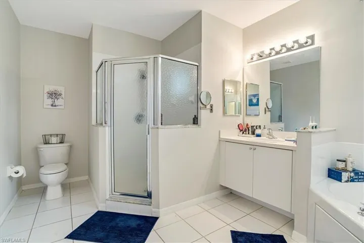 Full bathroom featuring tile flooring, oversized vanity, toilet, and separate shower and tub
