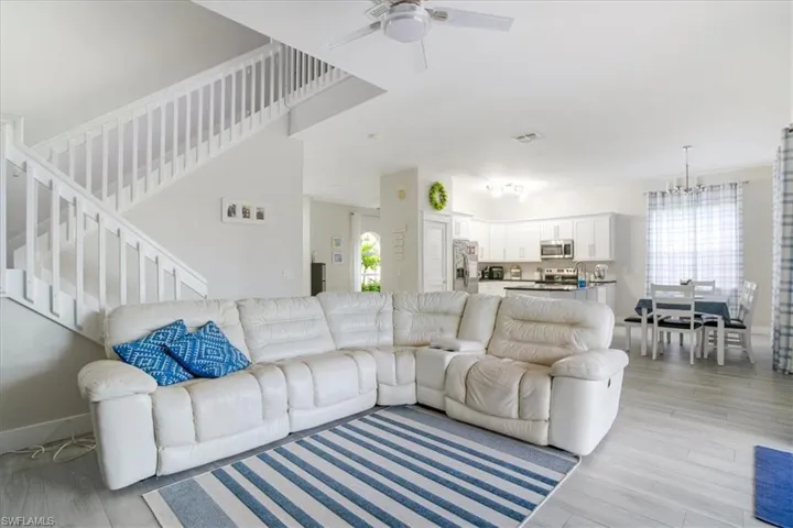 Living room with light hardwood / wood-style flooring and ceiling fan with notable chandelier