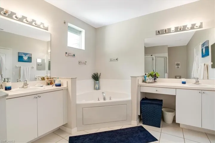 Bathroom featuring vanity with extensive cabinet space, separate shower and tub, and tile flooring