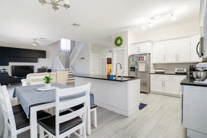 Kitchen with stainless steel appliances, sink, white cabinetry, and ceiling fan with notable chandelier