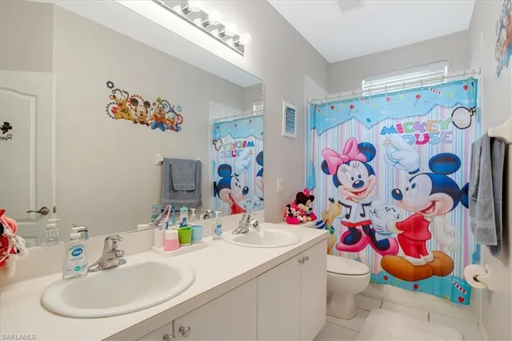 Bathroom featuring tile floors, large vanity, toilet, and dual sinks