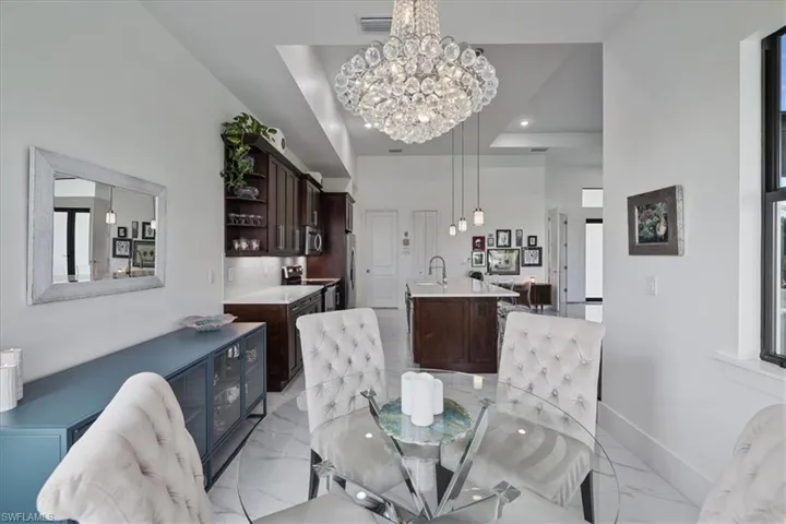 Dining space with light marble finish floors, a chandelier, a towering ceiling, and recessed lighting