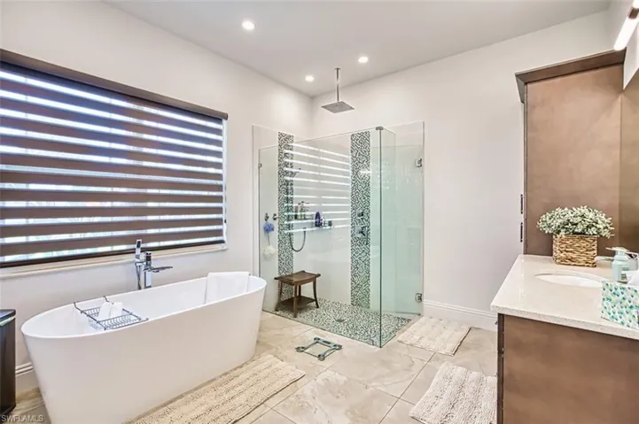Bathroom featuring a shower stall, a freestanding tub, vanity, recessed lighting, and tile patterned floors