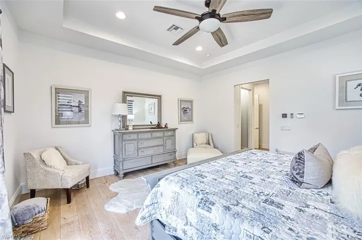 Bedroom with a tray ceiling, hardwood / wood-style floors, recessed lighting, and ceiling fan