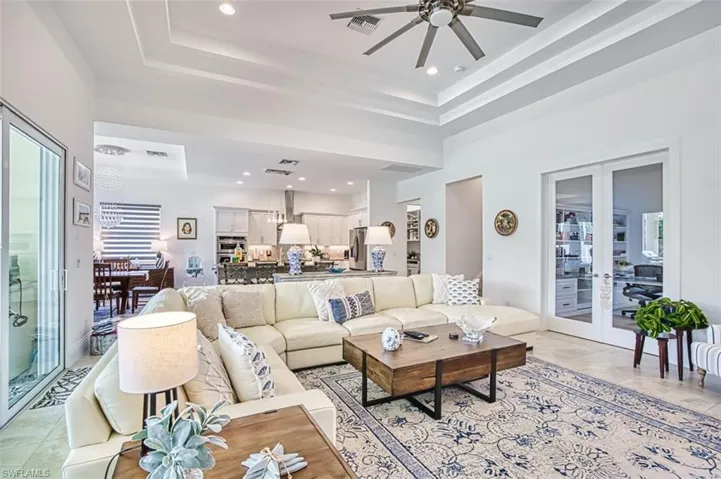Living room featuring french doors, a raised ceiling, recessed lighting, light tile patterned flooring, and ceiling fan