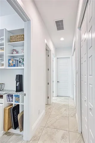 Hallway with light marble finish floors and recessed lighting