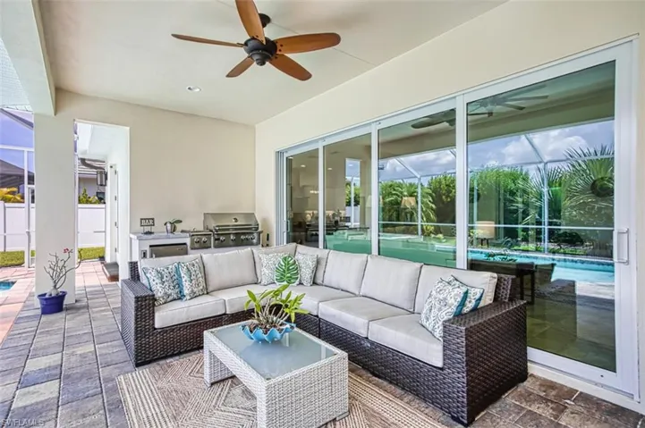 View of patio with exterior kitchen, a lanai, an outdoor pool, and ceiling fan