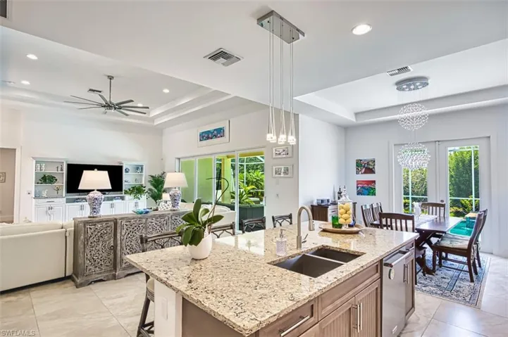 Kitchen with a tray ceiling, french doors, recessed lighting, hanging light fixtures, and a breakfast bar