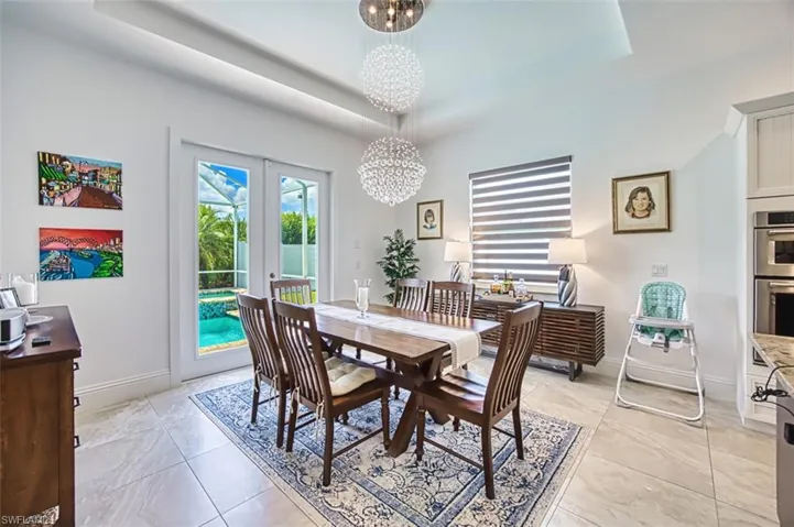 Dining room featuring a raised ceiling, a chandelier, and french doors