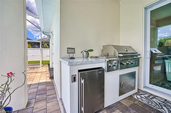View of patio featuring area for grilling and glass enclosure
