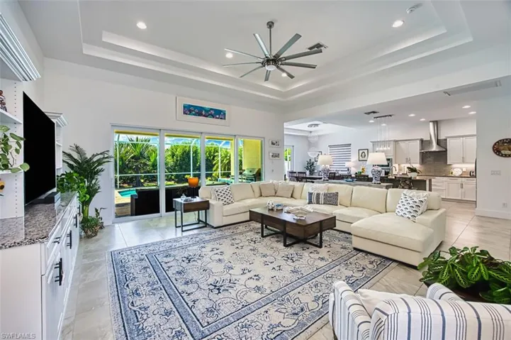 Living area with recessed lighting, a tray ceiling, a ceiling fan, and a high ceiling